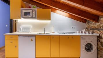 Cozinha compacta com máquina de lavar, micro-ondas e pia.