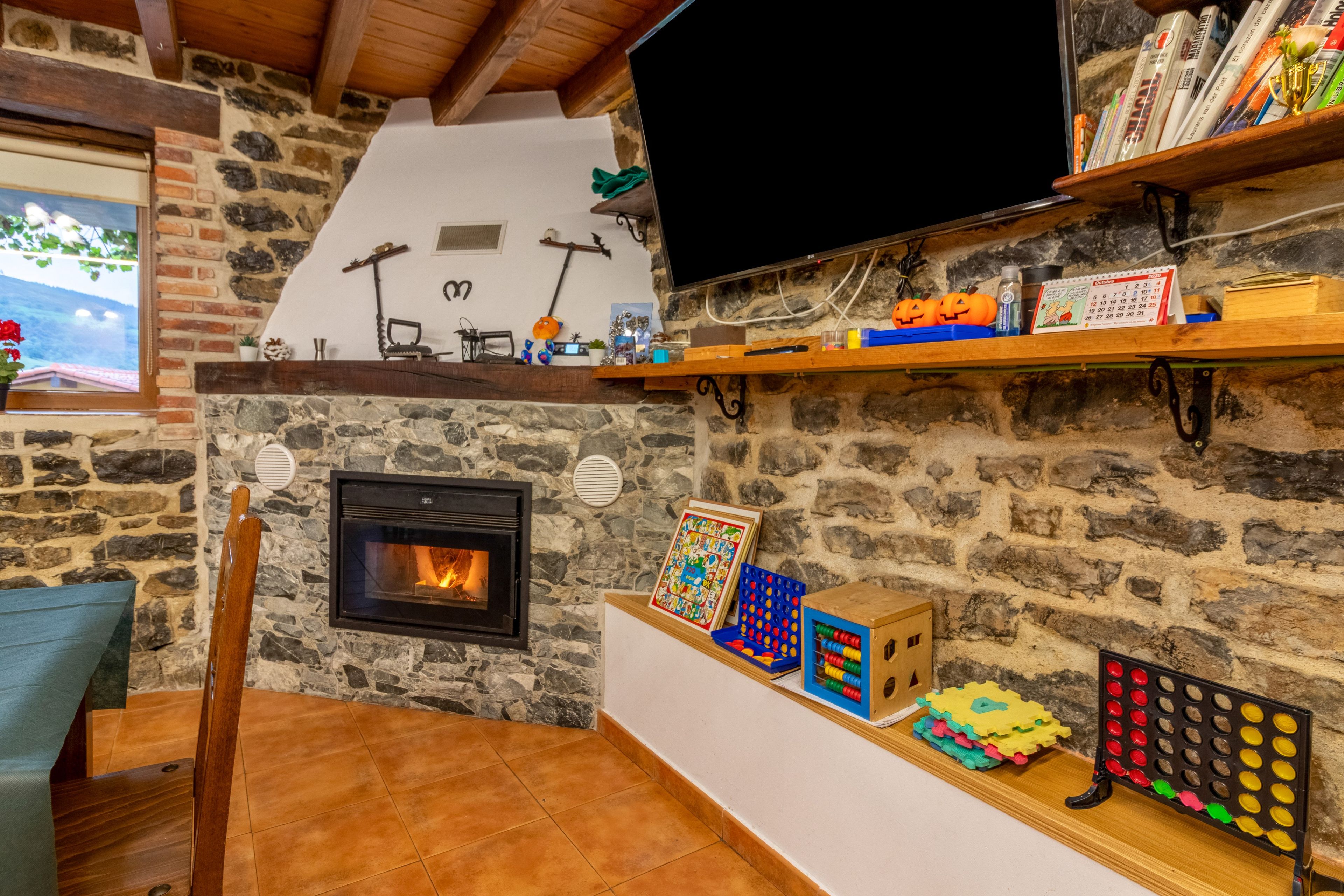Un saló confortable amb una llar de pedra, una televisió i diversos joguets i llibres infantils a les prestatgeries.