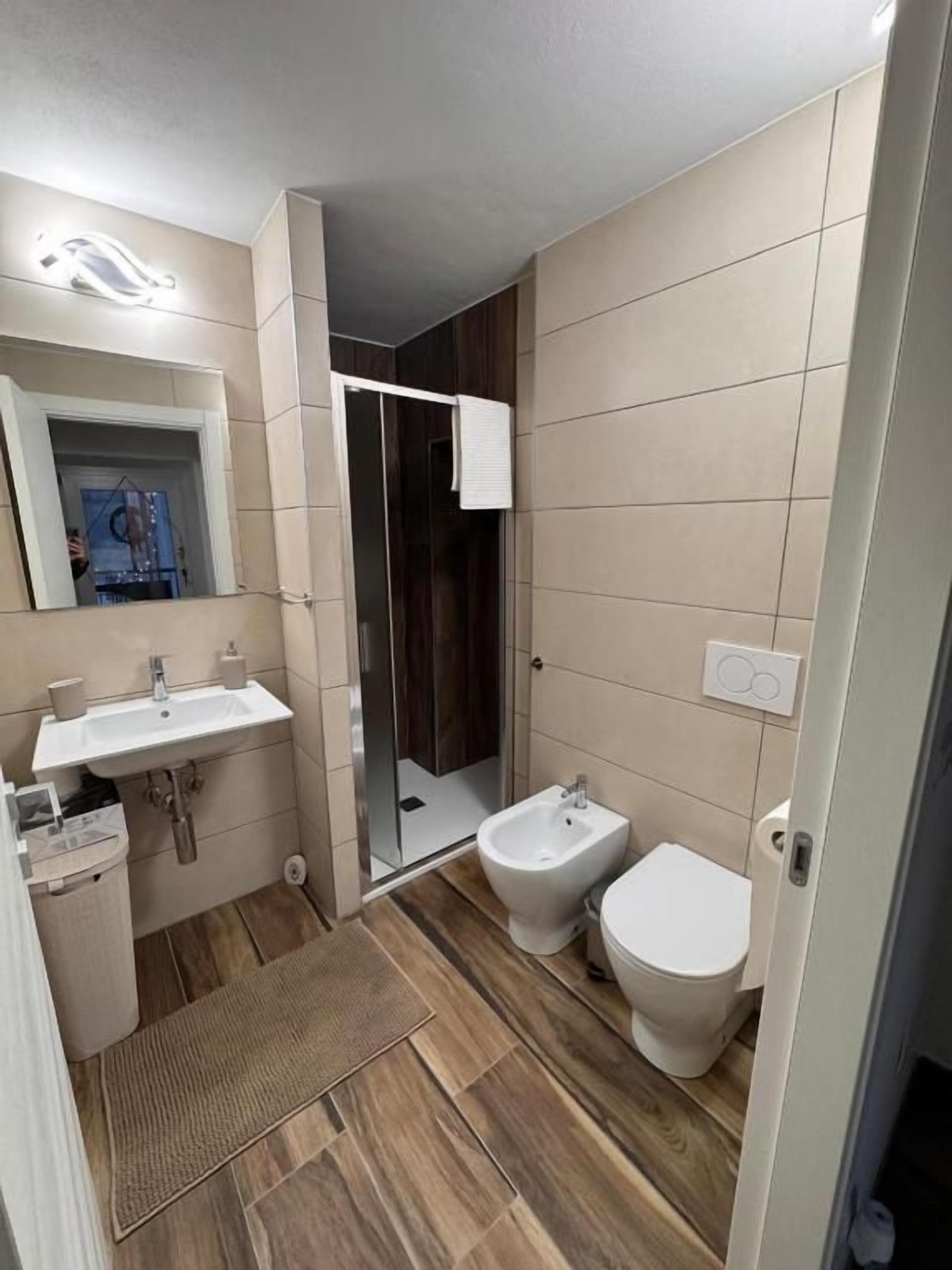A bathroom with a sink, bidet, toilet, and a shower area.