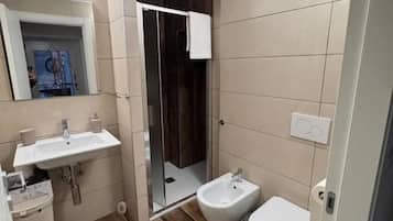 A bathroom with a sink, bidet, toilet, and a shower area.