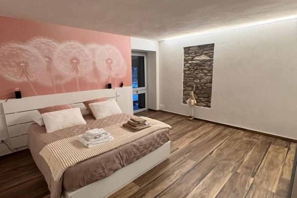 Un dormitorio con cama, pared de piedra y un mural de diente de león.