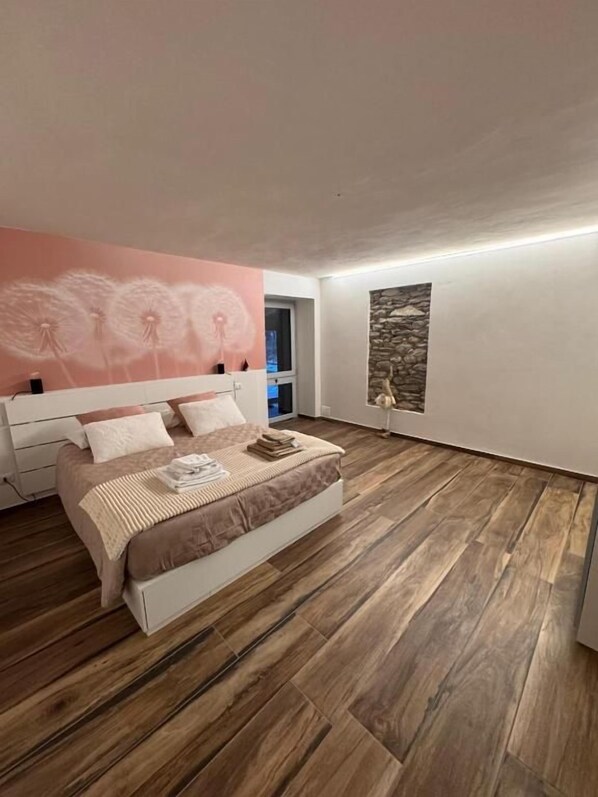 A bedroom with a bed, a stone wall, and a dandelion mural.