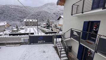 Ein Wohngebäude mit Balkon, Treppe und Blick auf eine verschneite Landschaft.