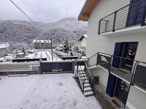 A residential building with a balcony, a staircase, and a view of a snow-covered landscape.