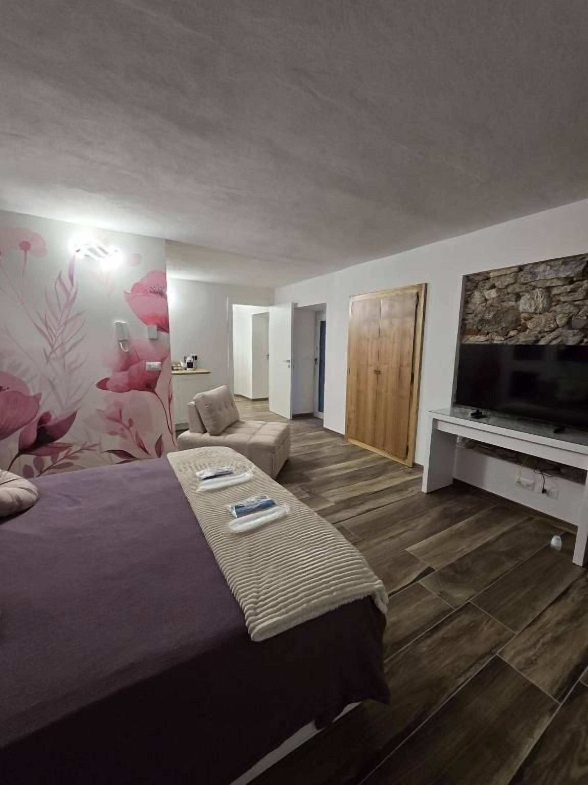 Una camera da letto con un letto, una TV, un armadio in legno e un bagno sullo sfondo.