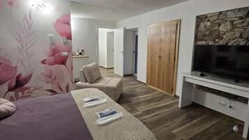 Una camera da letto con un letto, una TV, un armadio in legno e un bagno sullo sfondo.