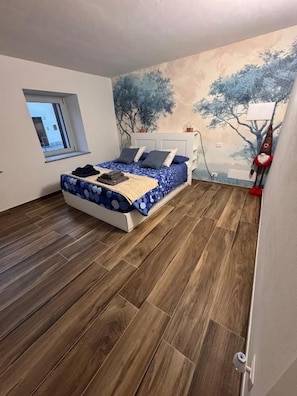 A bedroom with a bed, a window, and a mural on the wall. - B&B Blue Dragonfly (Paesana)