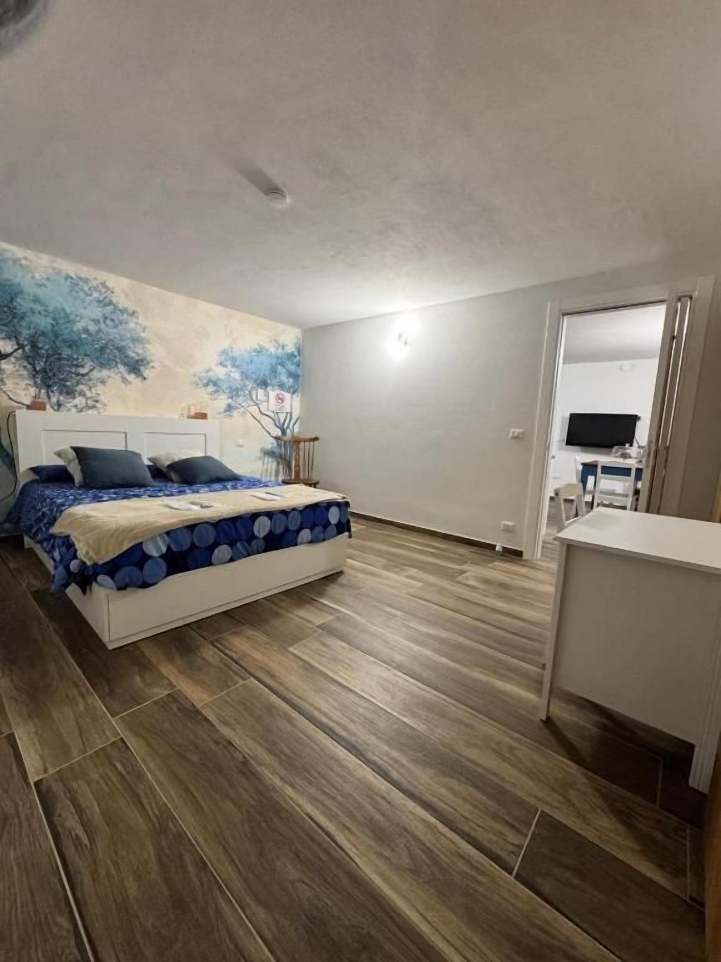 A bedroom with a bed, a desk, and a wall-mounted TV.