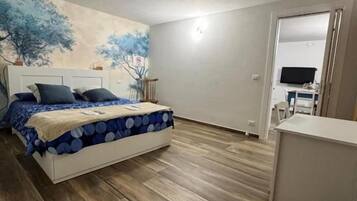 A bedroom with a bed, a desk, and a wall-mounted TV.
