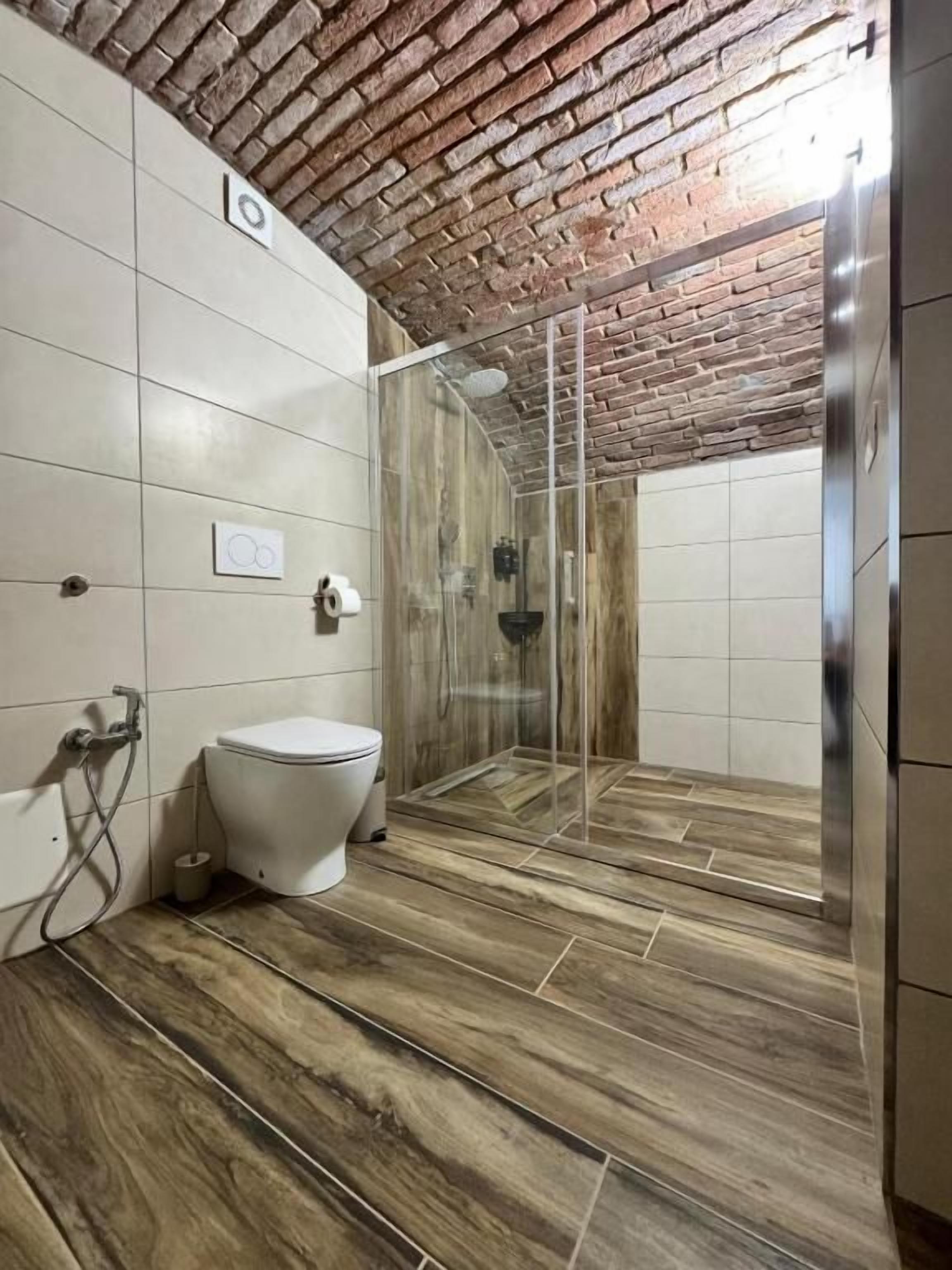 Un baño con ducha, inodoro y suelo de baldosas.