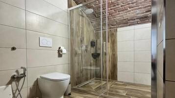 Un baño con ducha, inodoro y suelo de baldosas.