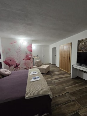 A bedroom with a bed, a bench, a television, and a wardrobe.