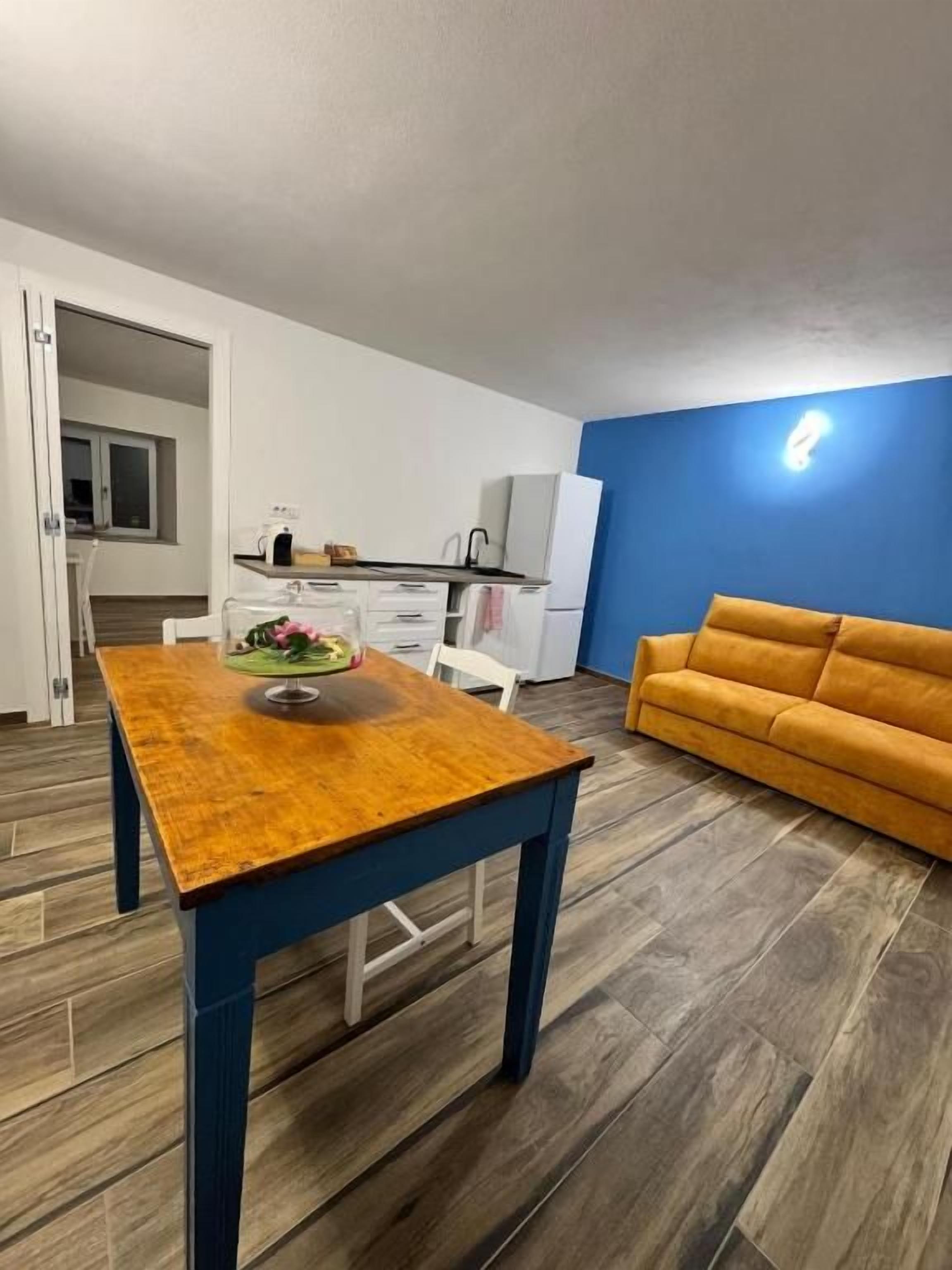 Una habitació amb taula de dinar de fusta, un sofà i una cuineta de fons.