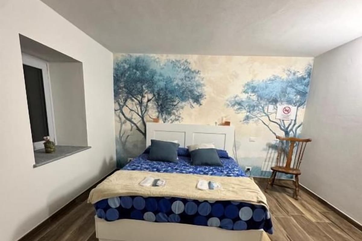A bedroom with a bed, a window, and a wall mural.