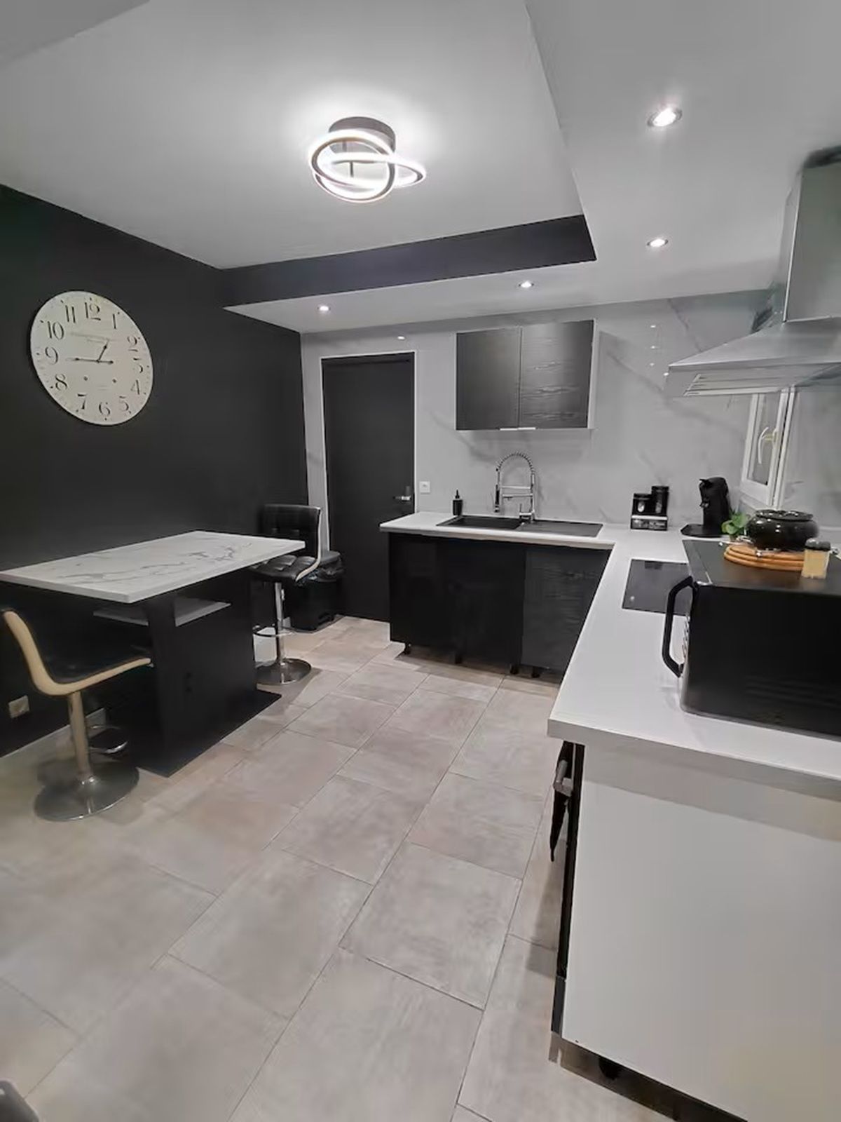A modern kitchen with a central island, a built-in sink, and a clock on the wall.