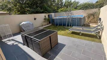Une terrasse sur le toit dotée d’un espace salon couvert, d’une petite piscine et d’une chaise longue.