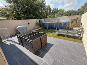 Eine Dachterrasse mit überdachter Sitzgelegenheit, einem kleinen Pool und einer Liege.