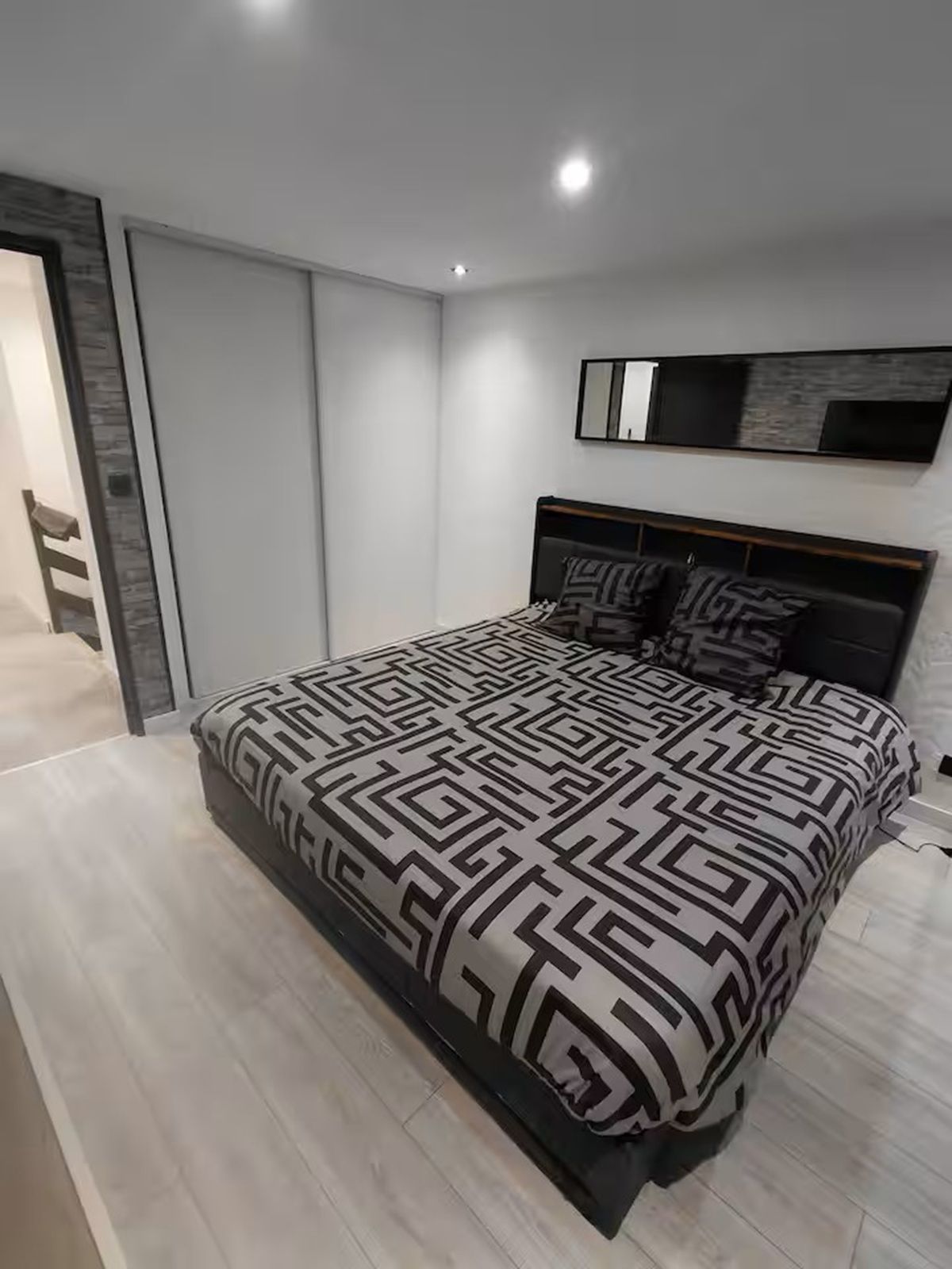 Une chambre à coucher moderne avec un lit, une armoire et un banc intégré.