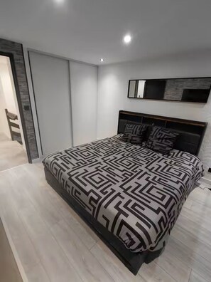 A modern bedroom with a bed, a wardrobe, and a built-in bench.