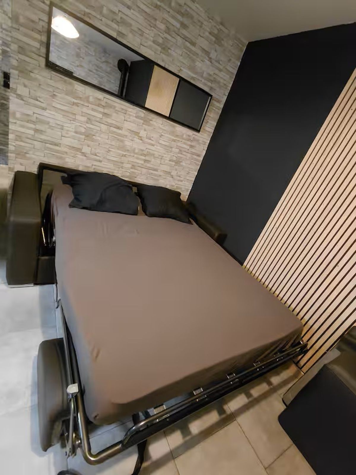 Une chambre moderne avec un lit, une petite table et une étagère fixée au mur.