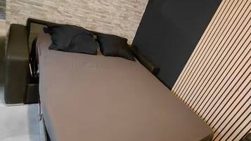 Une chambre moderne avec un lit, une petite table et une étagère fixée au mur.