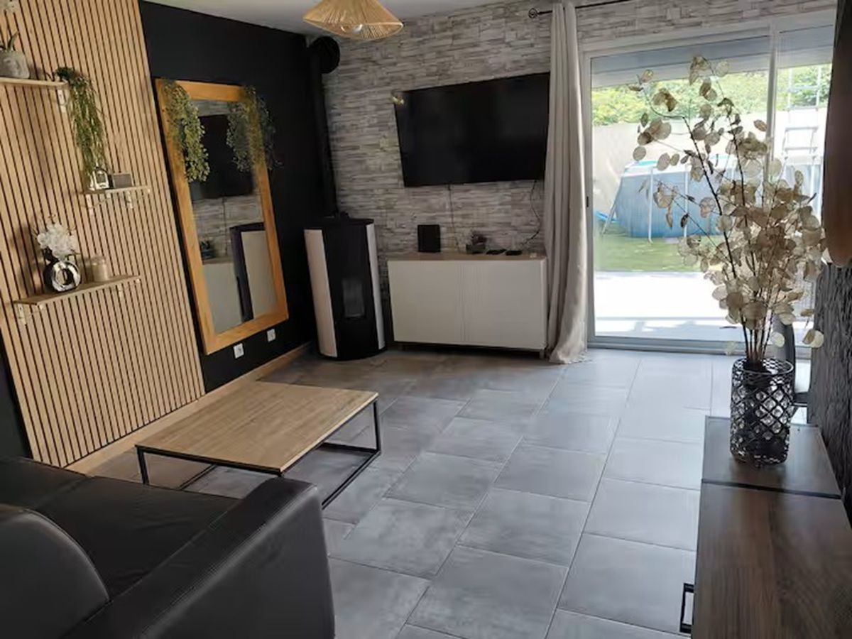 En moderne stue med et fladskærms-tv, en trævæg som detalje og et spiseområde.