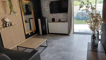 Un salon moderne doté d’un téléviseur à écran plat, d’un mur décoratif en bois et d’un coin repas.