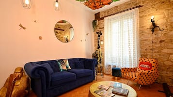 A living room with a blue sofa, a round coffee table with books, a giraffe statue, and a polka dot chair.