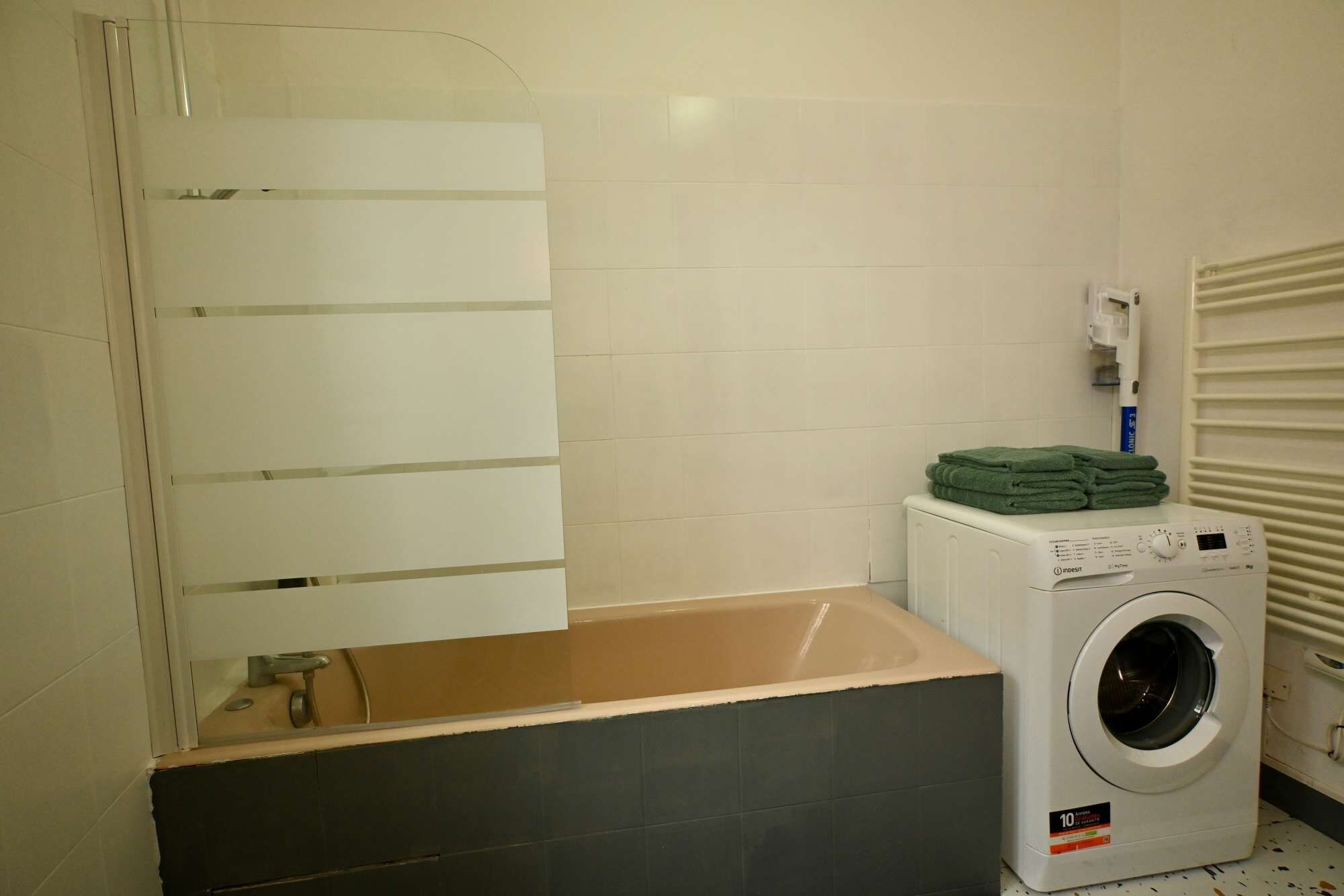 A laundry area with a washing machine, a drying rack, and a towel dispenser.
