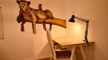 A room with a desk, chair, and a wall-mounted artwork of a cheetah and a bird.