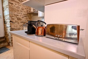 A kitchenette with a toaster, kettle, and coffee maker on a countertop. - Historic Center Apartment – Fireplace, Stone Walls & Jungle Decor (Vannes)