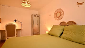 Un dormitorio con una cama, un escritorio con lámpara, un armario y decoración en la pared.