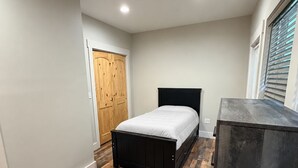 Quarto com cama, guarda-roupa e escrivaninha.