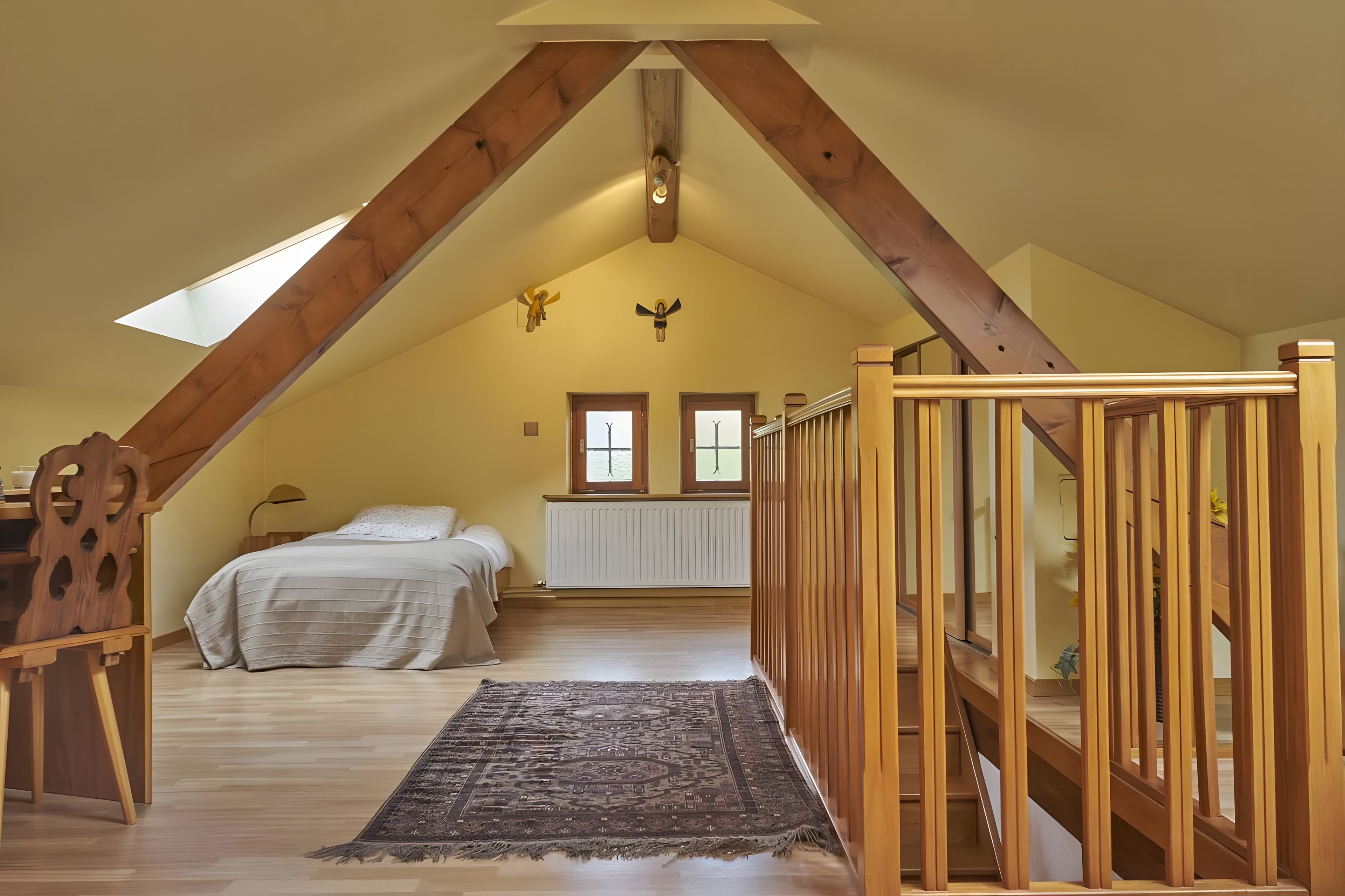 A bedroom with a sloped ceiling, wooden beams, a bed, a radiator, and a view through a window.