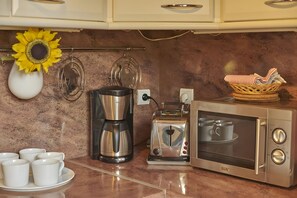 A kitchenette with a coffee maker, toaster, and microwave.