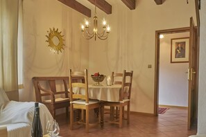 A dining area with a table, chairs, a chandelier, and a door with a painting.