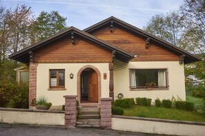 Een twee verdiepingen tellend huis met een schuine kap, een voordeur en een klein portaal.
