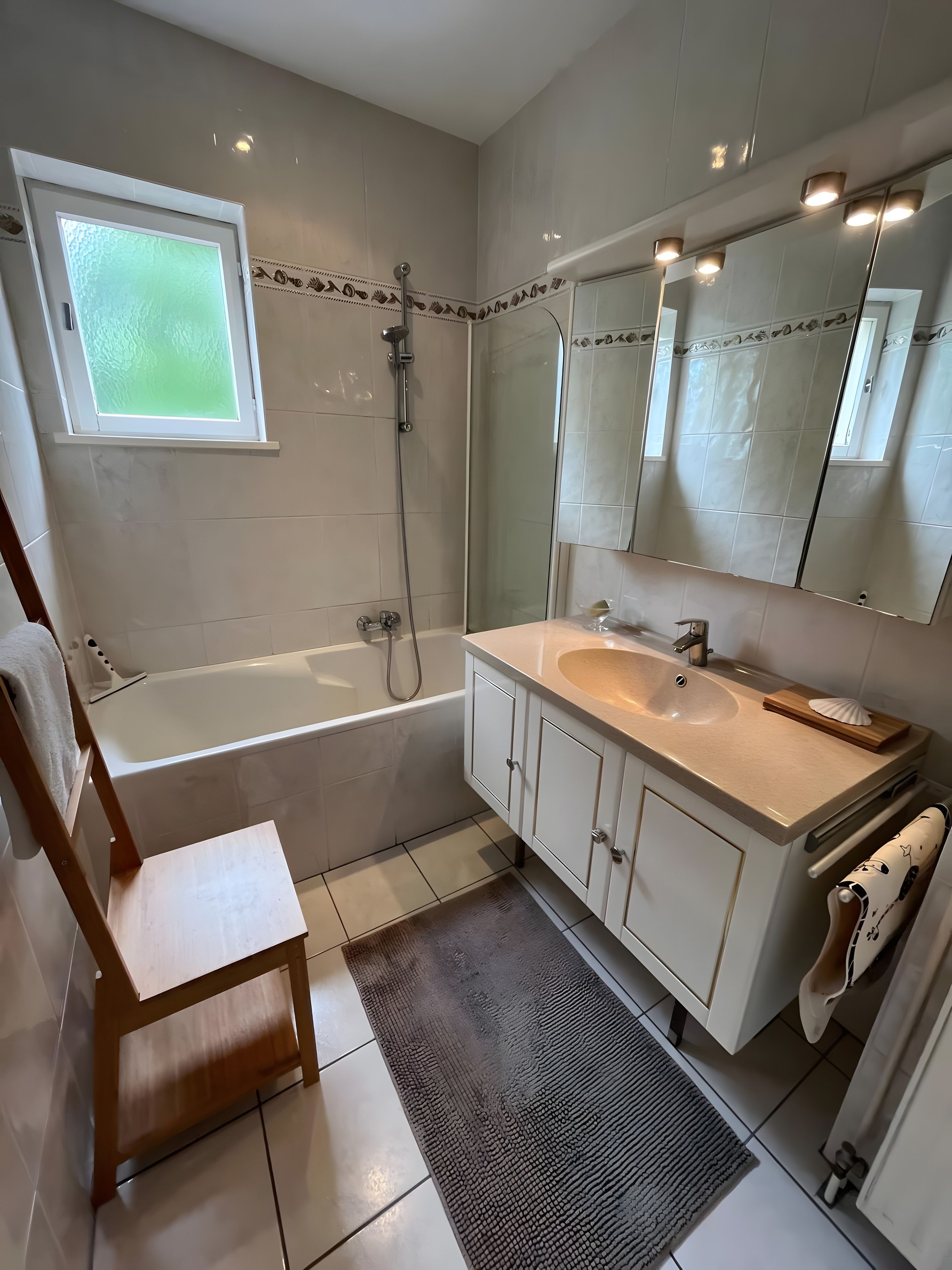 Une salle de bain moderne avec une baignoire, un grand miroir et un meuble-lavabo.