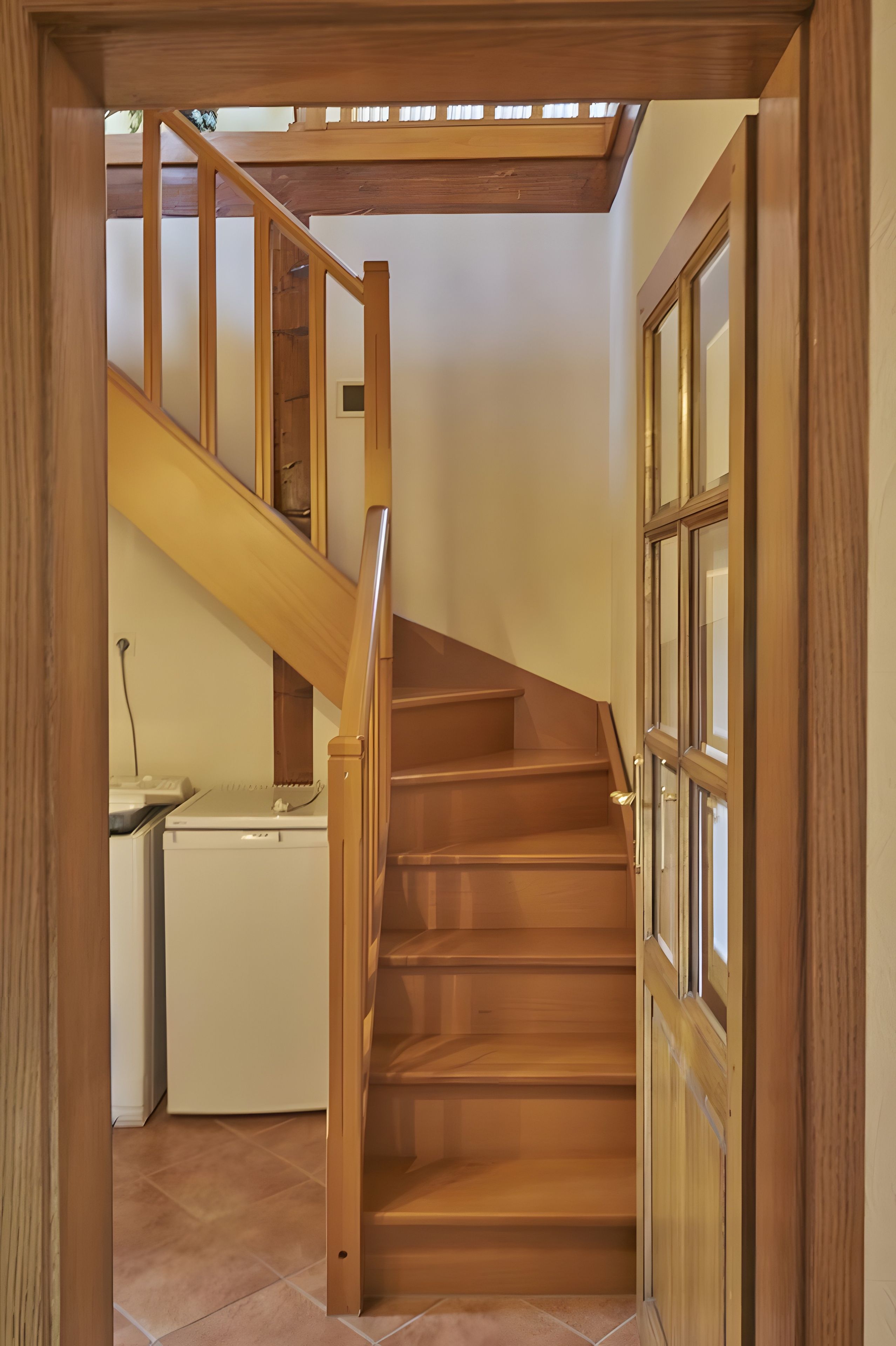 Eine Holztreppe führt zu einer oberen Etage mit einem Oberlicht darüber.