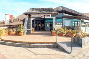 A building with a sign reading 'Residencial LAS DUNAS' and a covered entrance. - Casa Carmen " Pool View, Sunny Terrace & Fast Wi-Fi" (Corralejo)