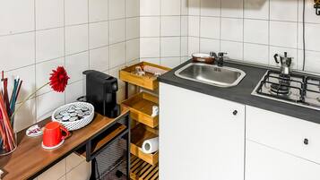 A compact kitchen with a sink, stove, and storage shelves.