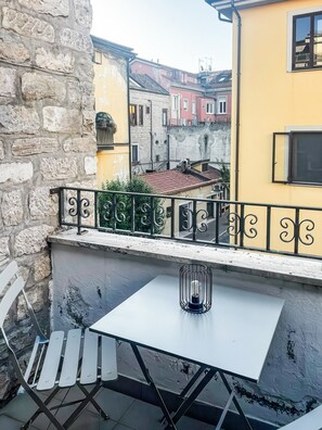 Un balcone con un tavolo e sedie bianche, una ringhiera in metallo e vista su edifici colorati.