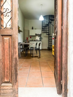 A kitchen with white cabinets, a dining table with chairs, a hanging light fixture, and a spiral staircase. - Le Dimore - Potenza: Three-Level Apartment in the Historic Center of Potenza (Potenza)