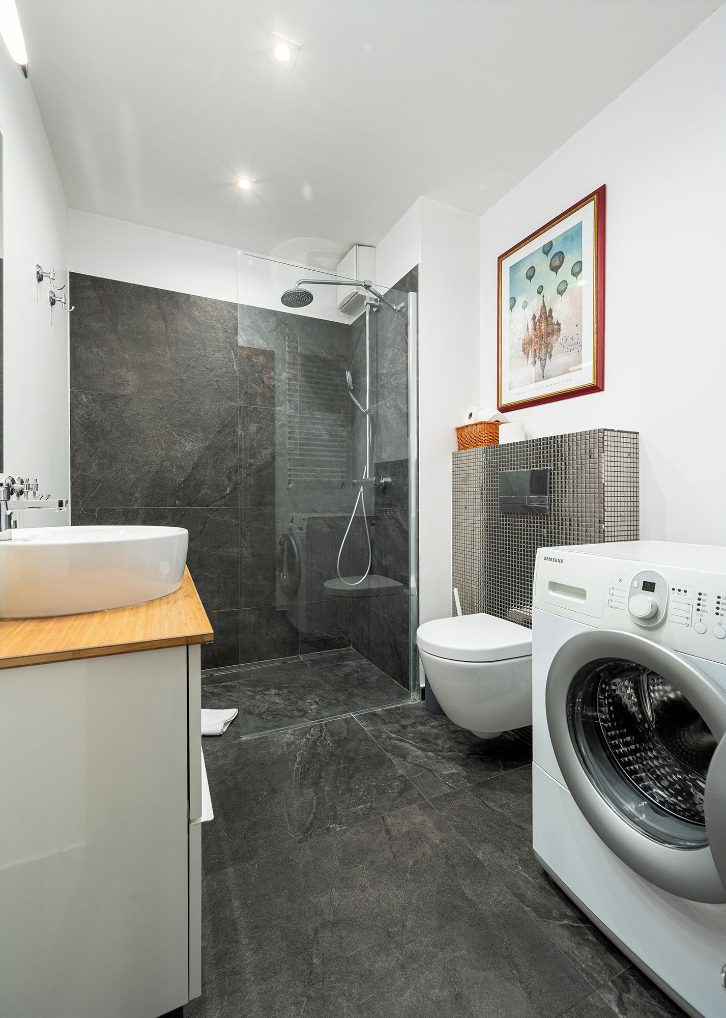 A modern bathroom with a shower, toilet, sink, and washing machine.