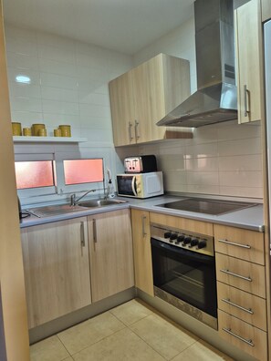 Eine moderne Küche mit Holzausstattung, einem eingebauten Backofen, einer Mikrowelle und einer Edelstahl-Dunstabzugshaube.