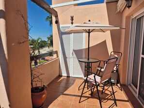 Ein Balkon mit Tisch und Stühlen, einem Blumentopf und Blick auf die Umgebung.