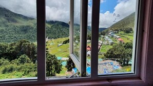 Blick aus dem Fenster auf ein Tal mit Straße, Häusern und viel Grün.