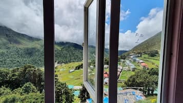 Vista desde una ventana que muestra un valle con una carretera, casas y vegetación.
