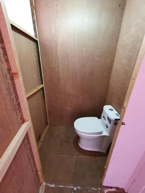 Een kleine badkamer met een wit toilet, een douche en een roze wand.
