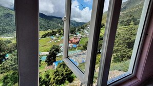 Blick aus dem Fenster auf eine gebirgige Landschaft mit einem Dorf darunter.